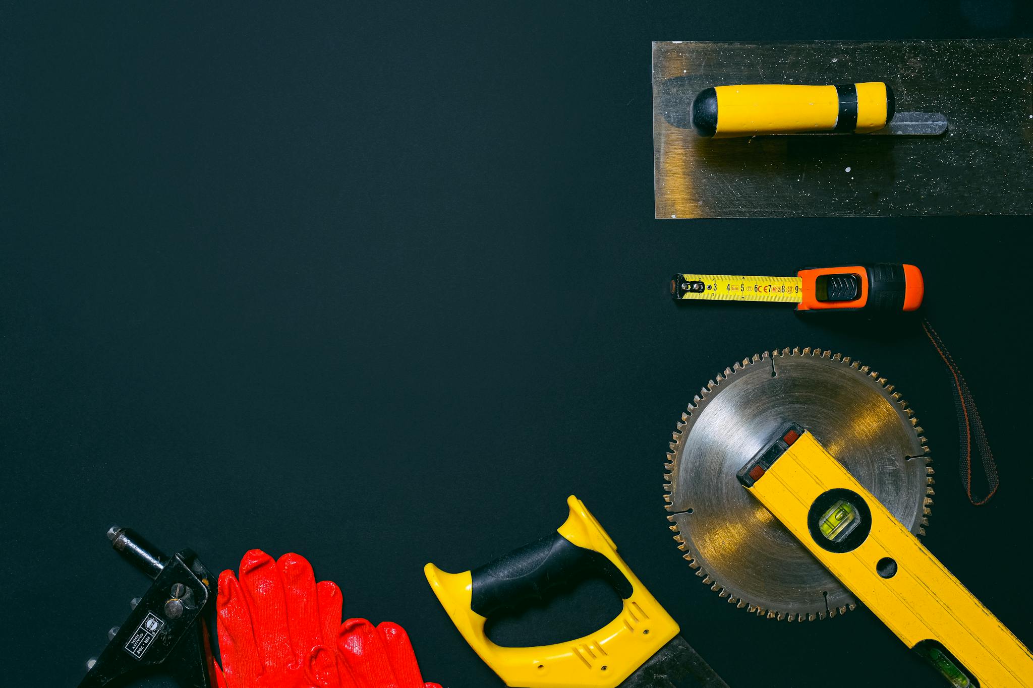 A variety of construction tools arranged on black surface for a flat lay composition.